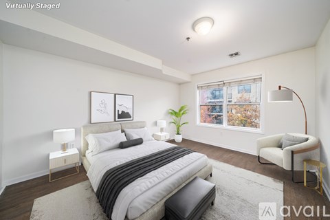 A bedroom with a large bed and a chair.