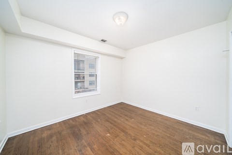 A room with wooden flooring and a window with blinds.