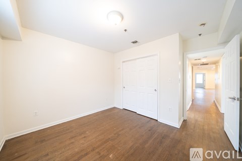 A long hallway with wood floors and white walls.