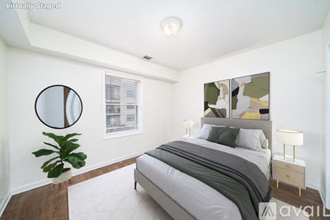 A bedroom with a bed, a plant, and a painting on the wall.
