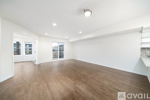 A spacious room with wooden flooring and white walls.