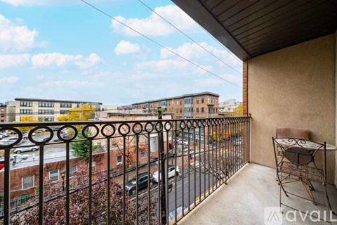 A balcony with a metal railing and a chair overlooking a street.
