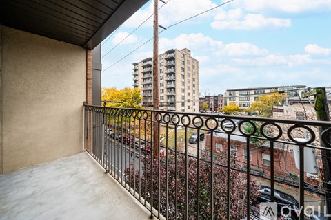 A balcony with a metal railing overlooks a city street.