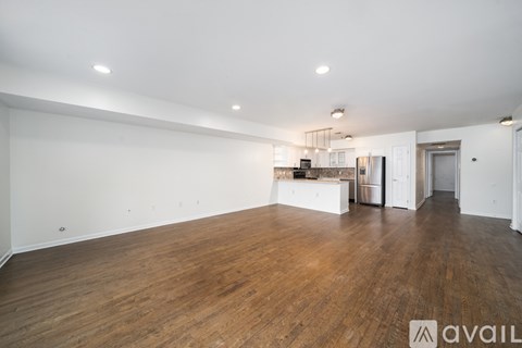 A spacious room with wooden floors and white walls.
