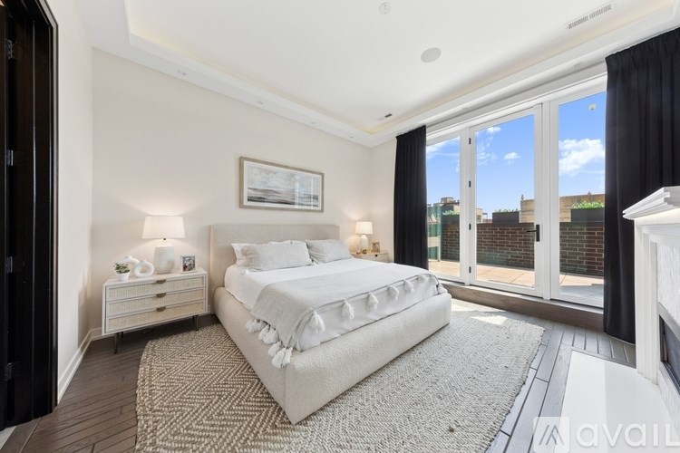 A bedroom with a large bed, a dresser, and a window with a view of the city.