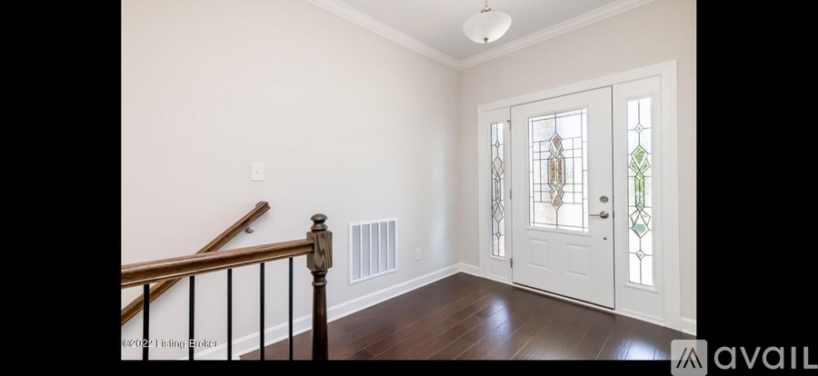 A hallway with a staircase and a door with a glass window.
