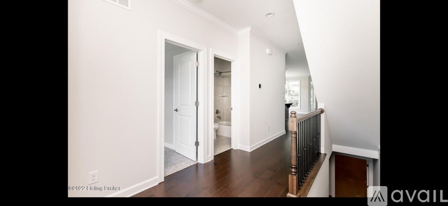 A hallway with a white door and a balcony with a railing.