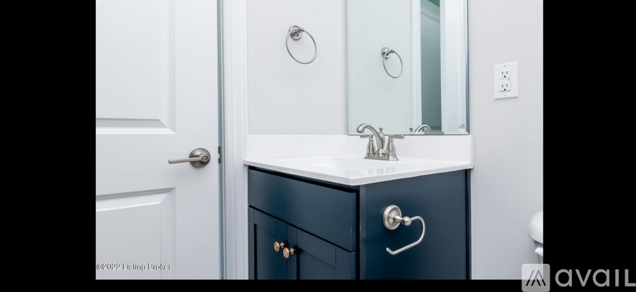A bathroom with a white sink and a black cabinet.