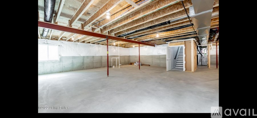 A large empty room with a staircase and a window.
