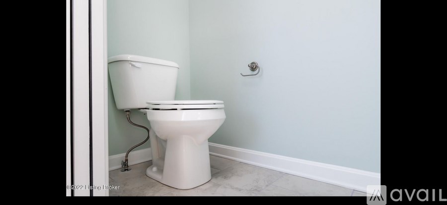 A white toilet is in a bathroom with light blue walls.