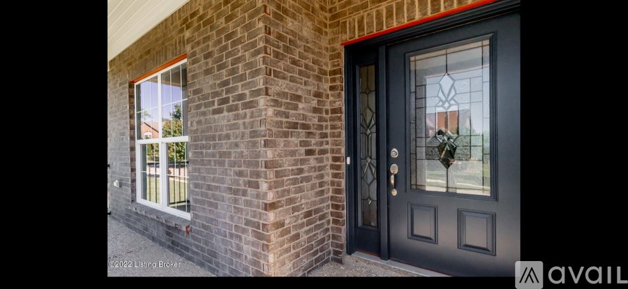 A black door with a glass window is on a brick wall.