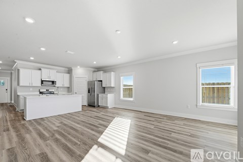 A spacious kitchen with white cabinets and a wooden floor.