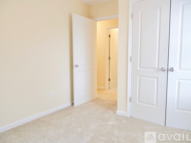 A room with a carpeted floor and two white doors.