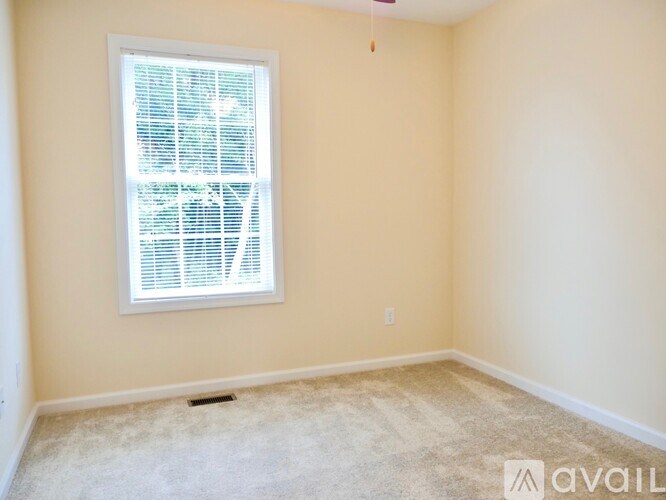 A room with a window covered in blinds and carpet on the floor.