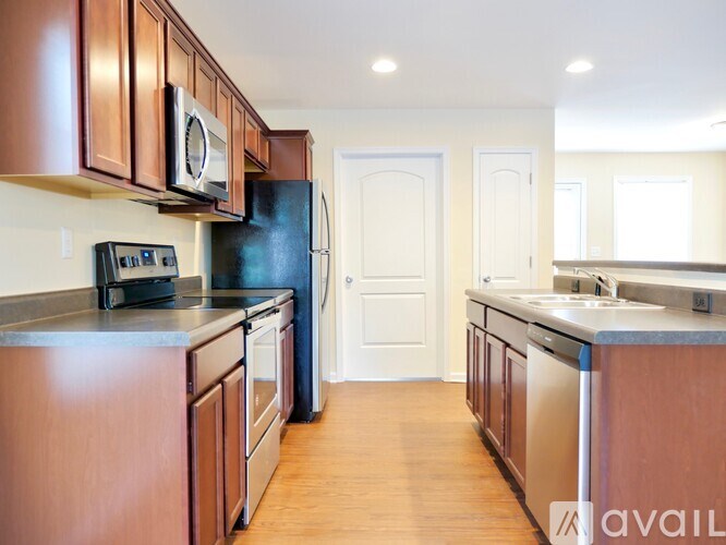 A kitchen with brown cabinets and a black fridge.