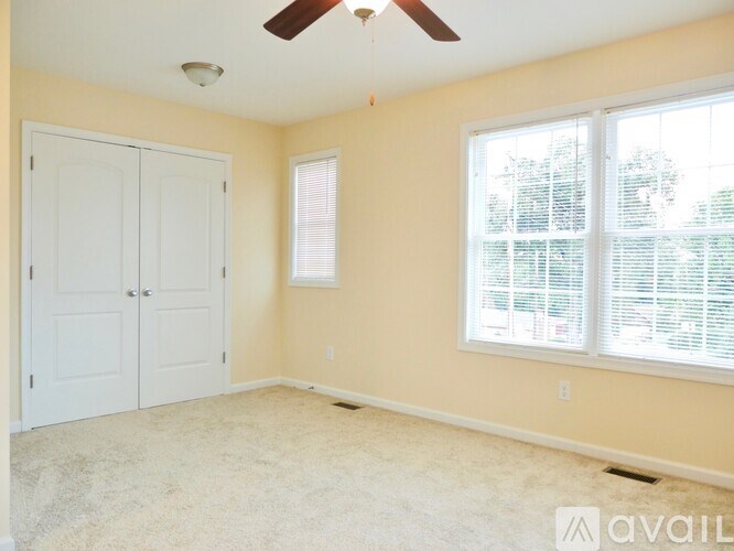 A room with a ceiling fan and a window with blinds.