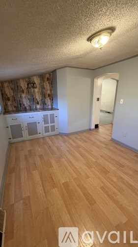 A room with wooden flooring and a wall with a wood panel design.
