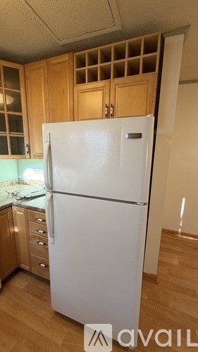 A white refrigerator in a kitchen with wooden cabinets.