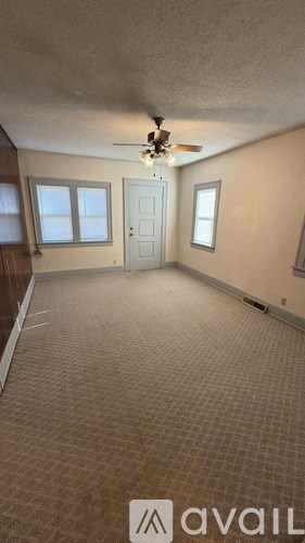 A room with a carpeted floor and a ceiling fan.
