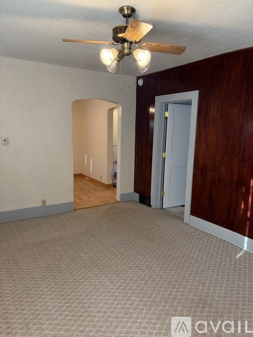 A room with a ceiling fan and carpeted floor.