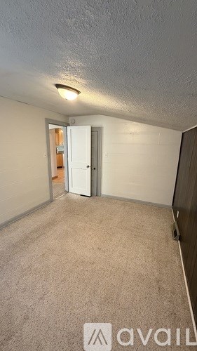 A carpeted room with a doorway leading to another room.
