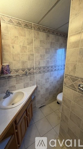 A bathroom with a sink, toilet, and tiled walls.