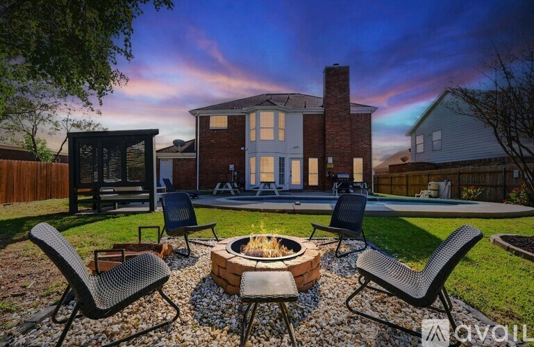 A backyard with a fire pit and chairs.