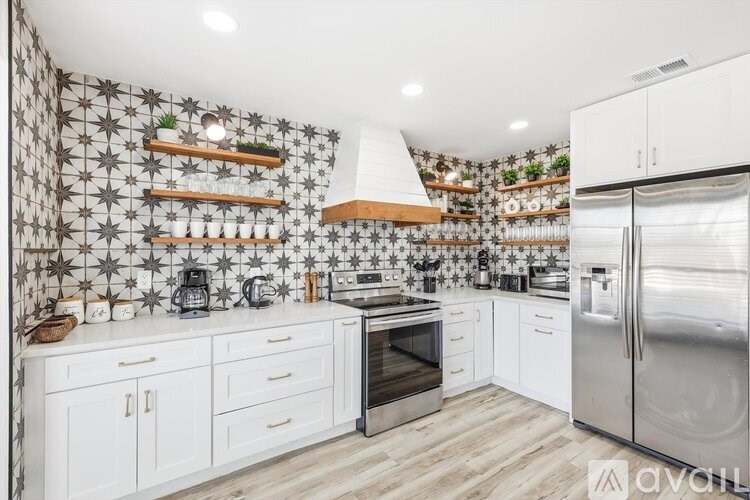 A kitchen with white cabinets and a patterned wallpaper.
