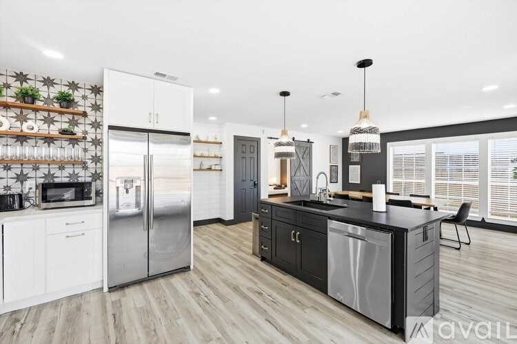 A modern kitchen with a black countertop and stainless steel appliances.