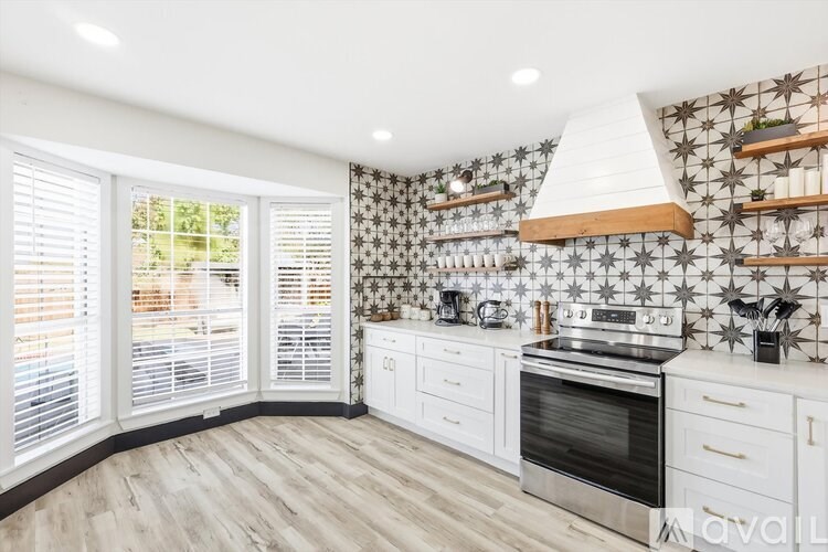 A kitchen with a white oven and a black and white tiled backsplash.