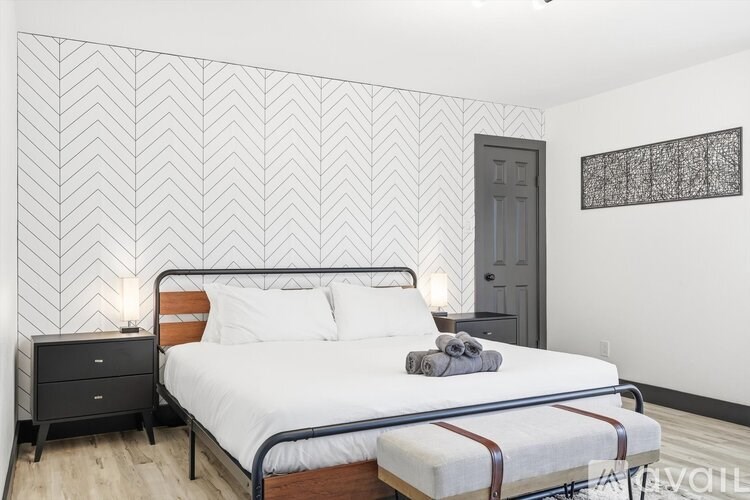 A bedroom with a bed, nightstand, and a wall with a zigzag pattern.