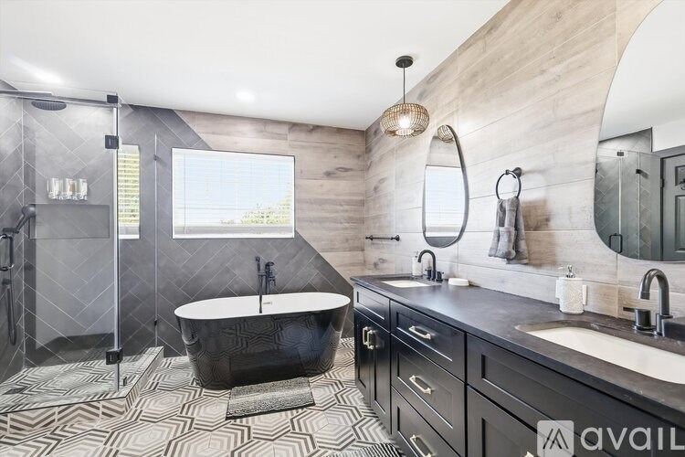 A modern bathroom with a black tub and sink.
