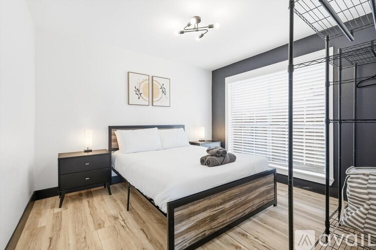 A bedroom with a large bed, a nightstand, and a chair.