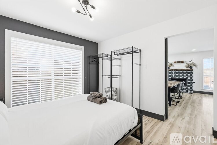 A bedroom with a white bed and a wooden floor.