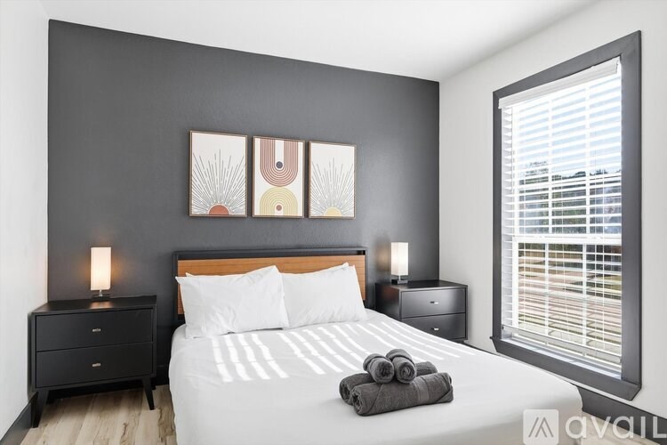 A bedroom with a large bed, two nightstands, and a window with blinds.