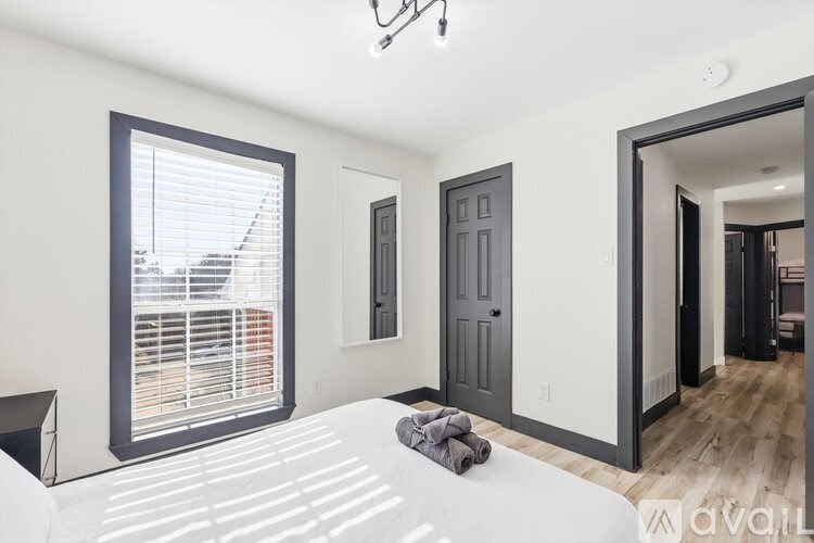 A bedroom with a large bed and a window with blinds.