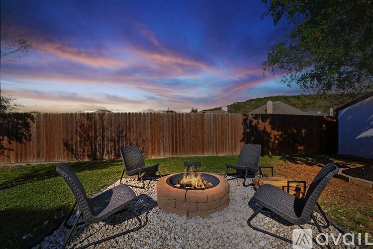 A backyard with a fire pit and chairs.