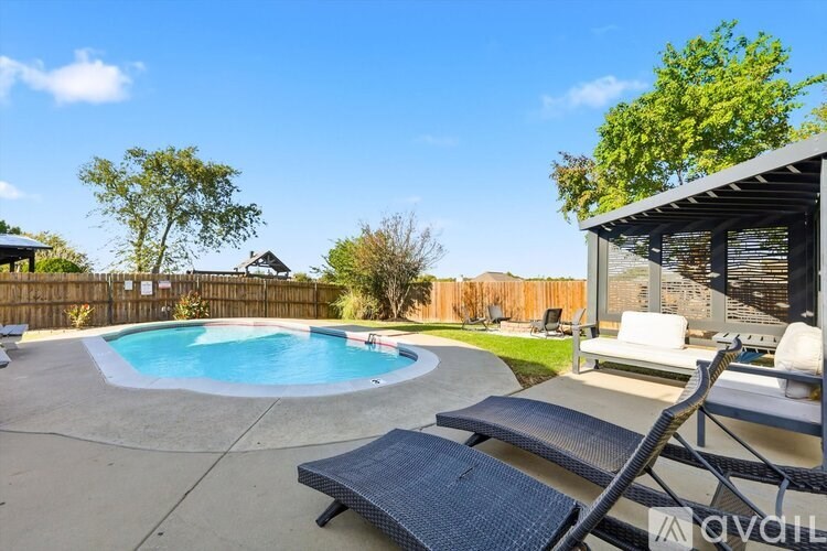 A backyard with a pool and lounge chairs.