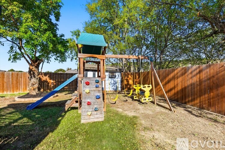 A wooden play structure with a blue slide and a green roof.