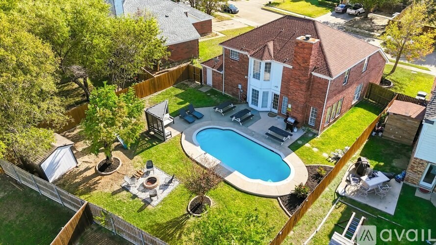 A house with a red brick exterior and a pool in the backyard.