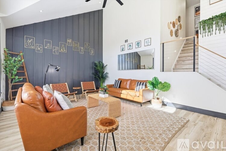 A living room with a brown sofa, a wooden coffee table, and a staircase in the background.