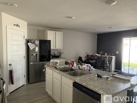A kitchen with a black fridge and white cabinets.