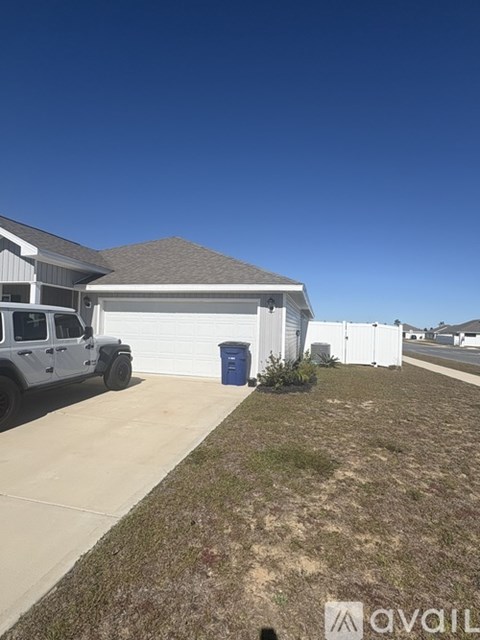 A white house with a blue trash bin in front.