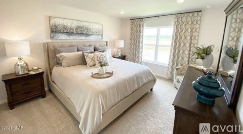 A bedroom with a large bed, a nightstand with a lamp, and a painting on the wall.