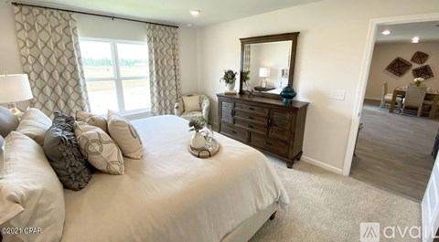 A bedroom with a large bed, a dresser, and a mirror.