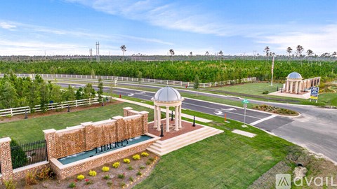 A gazebo is surrounded by a brick wall and a green lawn.