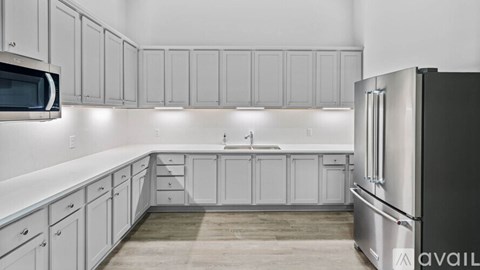 A kitchen with white cabinets and a black refrigerator.