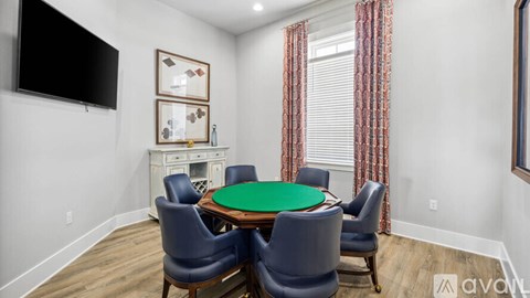 A room with a green table surrounded by chairs.