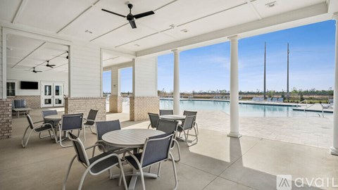 A patio with a table and chairs overlooking a pool.