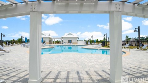 A pool area with a white pergola and a blue pool.